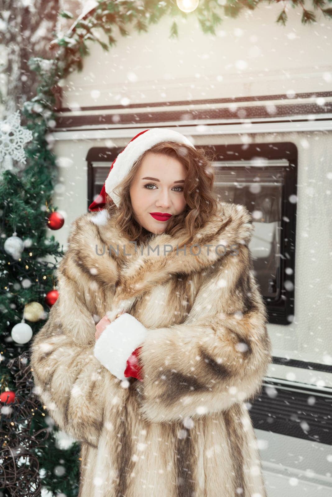 Young woman in fur coat with gift box at winter campsite getting ready for the new year.