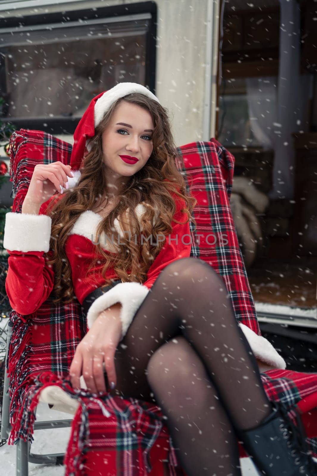 Young woman in santa costume resting at winter campsite. New year celebration concept