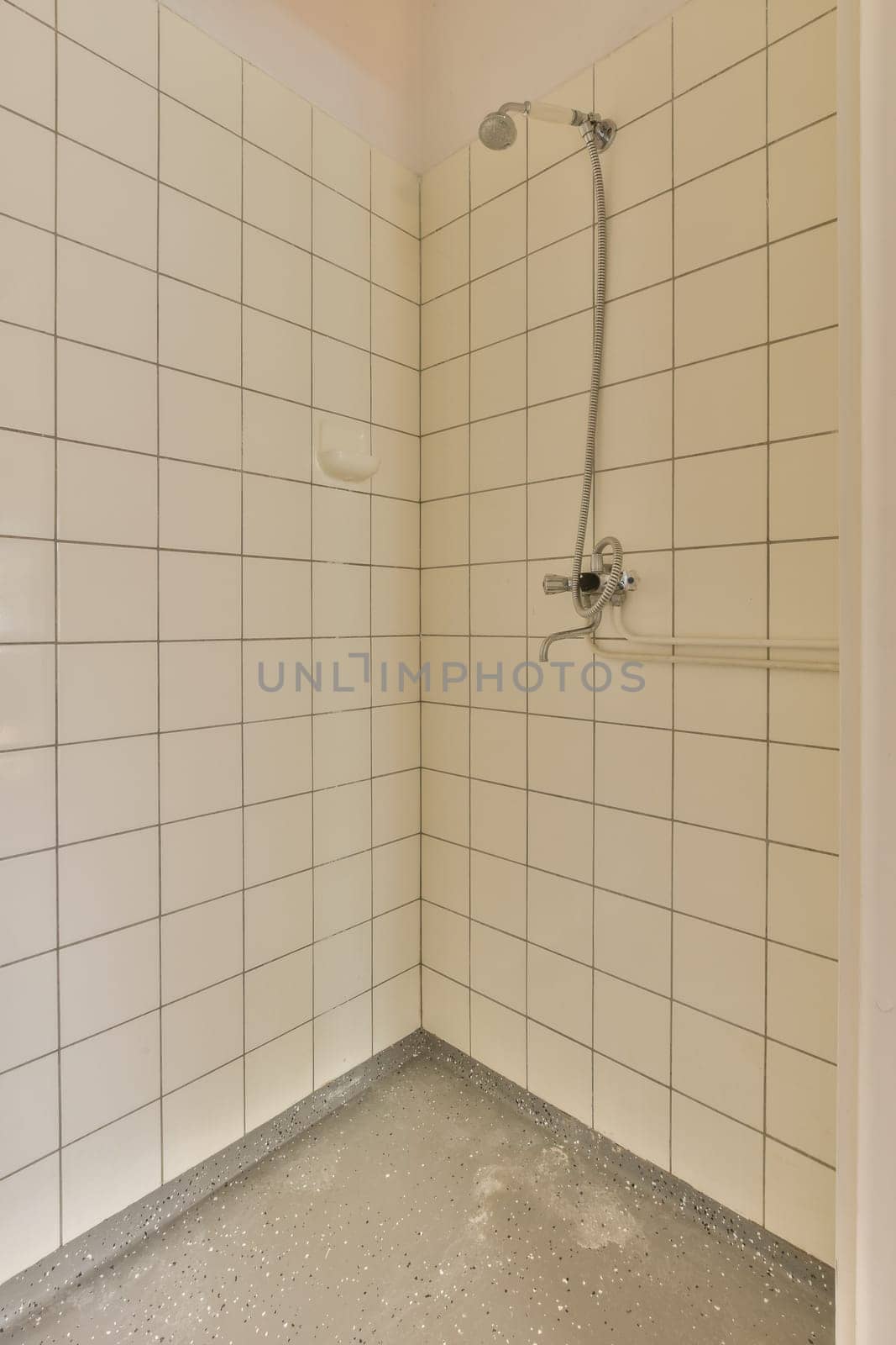 a shower stall with white tiles on the walls and floor in an empty room, it appears to be used as a bathroom