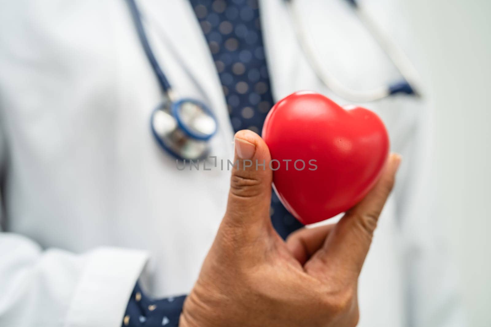 Doctor holding a red heart in hospital ward, healthy strong medical concept. by pamai