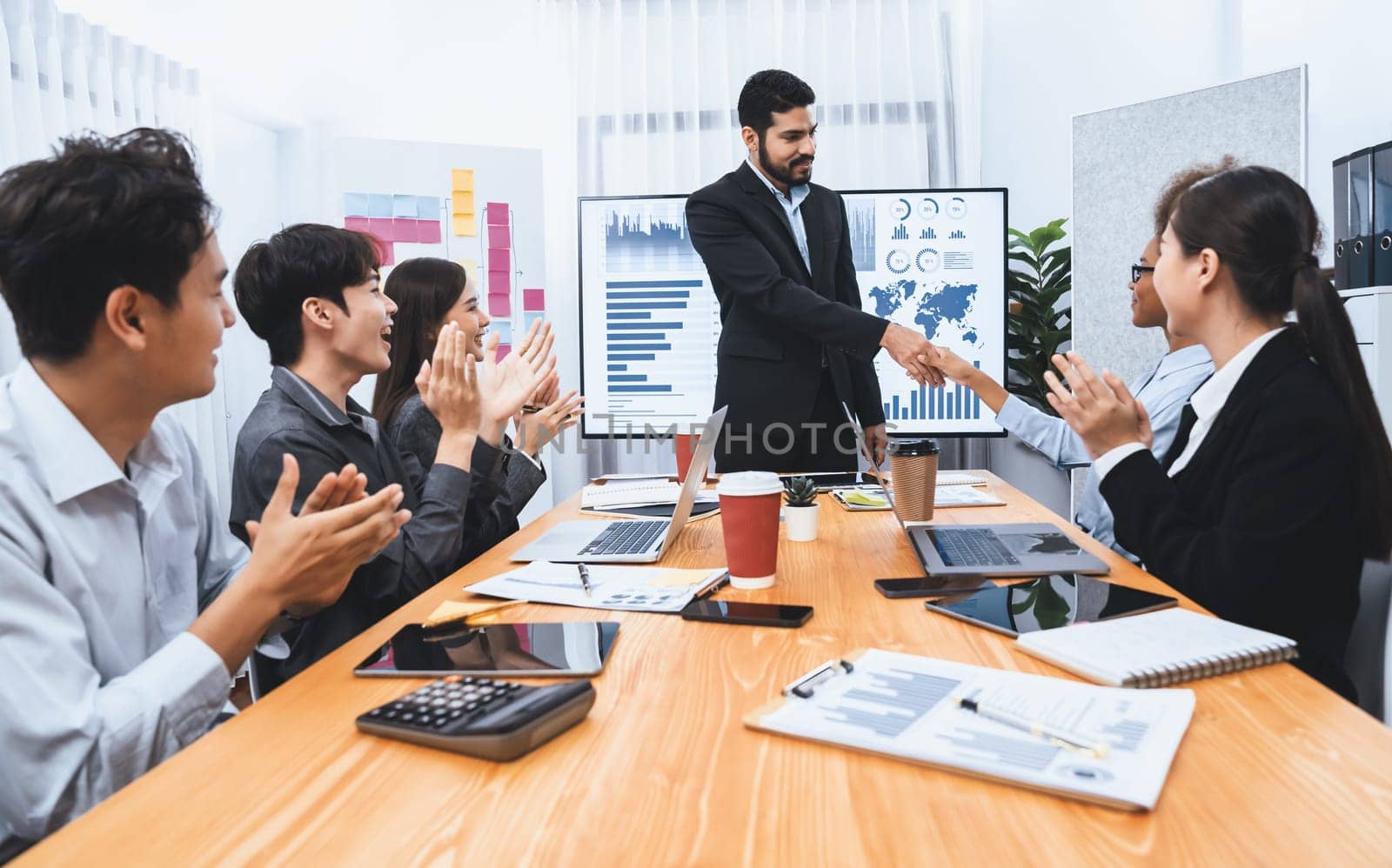 Diverse coworker celebrate with handshake and teamwork in corporate workplace. Happy business people united by handshaking after successful meeting or business presentation on data analysis. Concord