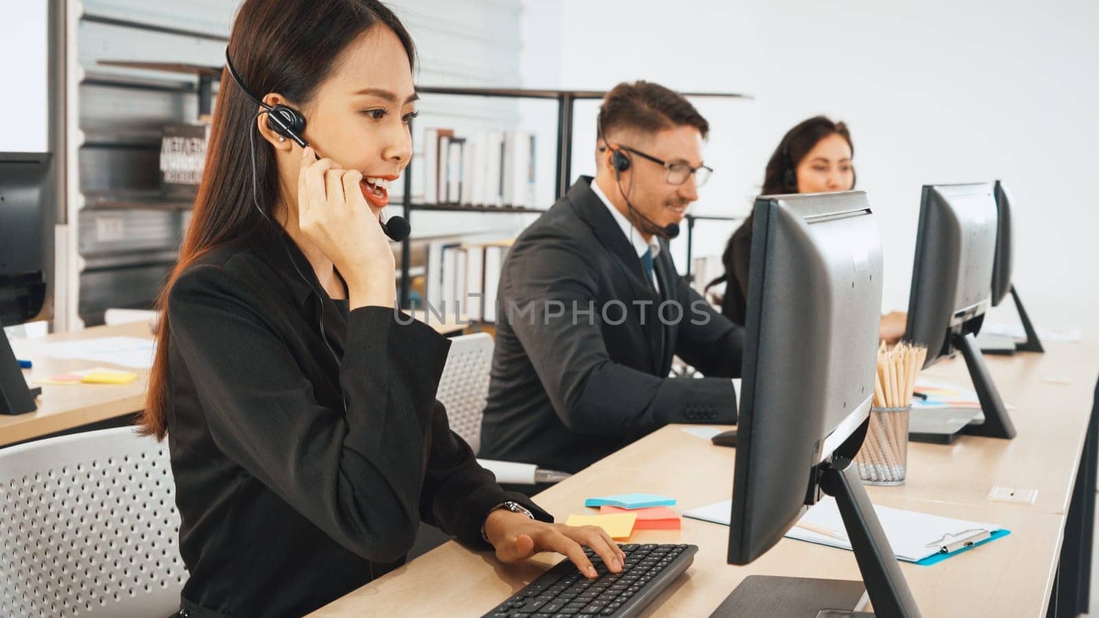 Business people wearing headset working in office to support remote customer or colleague. Call center, telemarketing, customer support agent provide service on telephone video conference call. Jivy