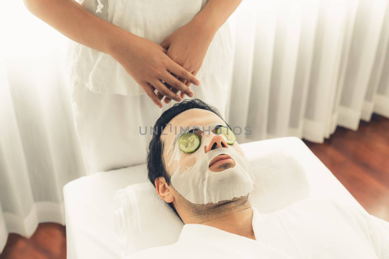 Man customer indulges in rejuvenating with cucumber facial care. Quiescent by biancoblue