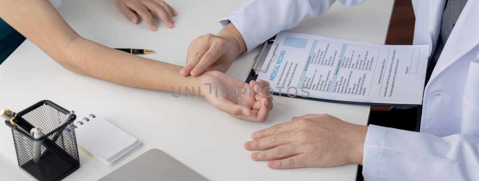 Patient attend doctor's appointment at clinic or hospital office. Doctor discusses medical treatment option, examining and diagnosis symptoms while checking the patient's pulse. Panorama Rigid