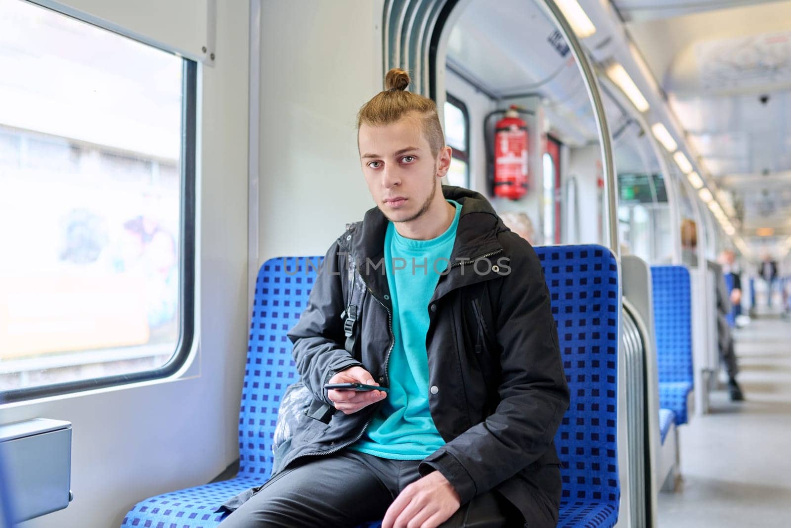 Young male passenger sitting inside an electric intercity train by VH-studio