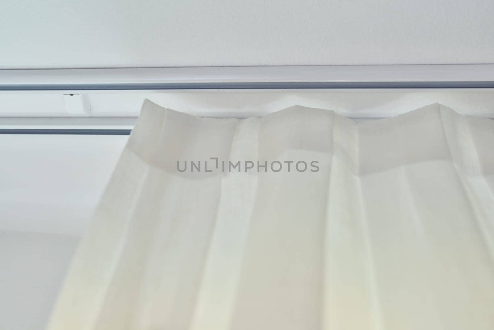 Translucent white textured curtain on window, close-up of cornice and fabric gathered on braid by VH-studio