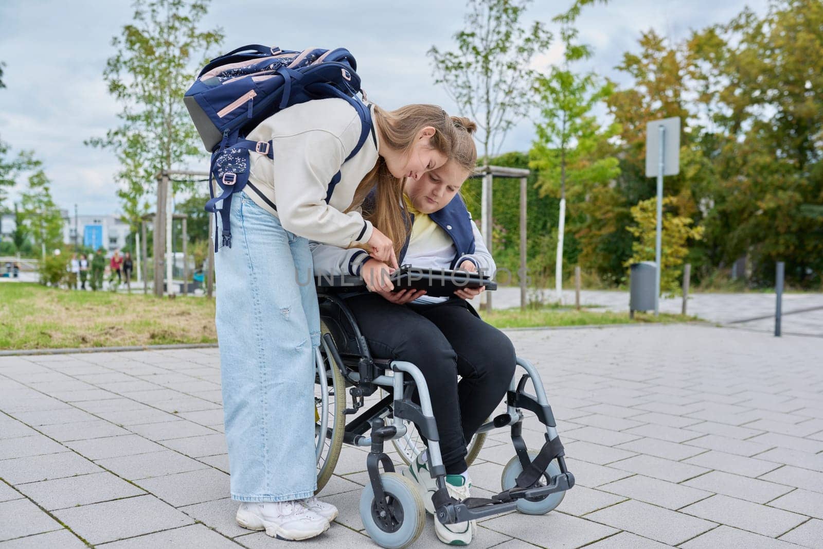 Children together outdoor, girl and boy on wheelchair talking near school building by VH-studio