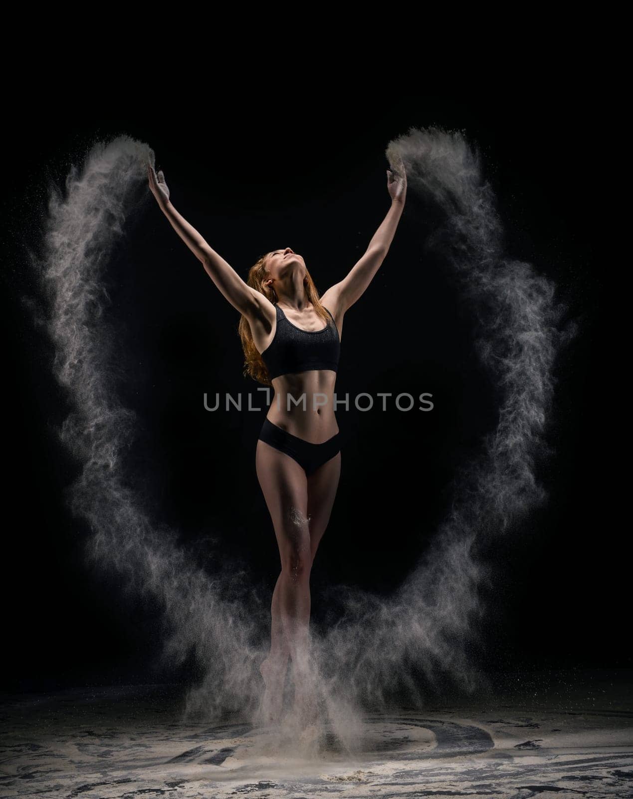 fit woman in underwear jump and making circle of sand in air while dancing