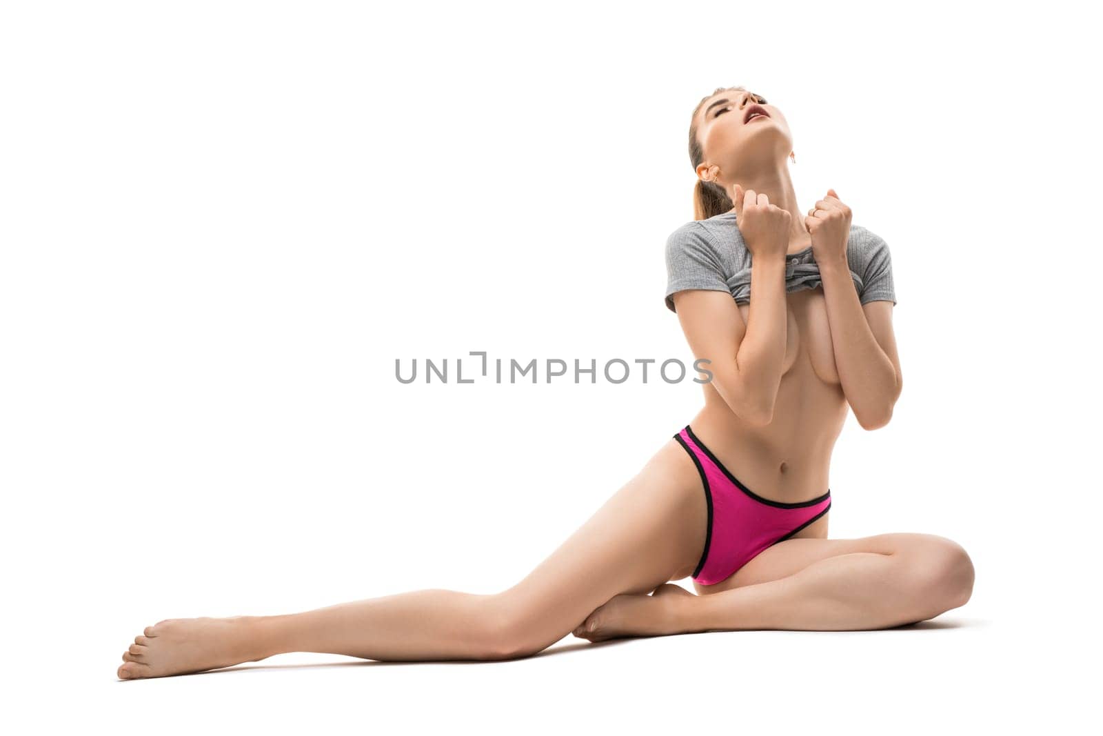 Fit young woman in bright panties close eyes and undress grey top against white background
