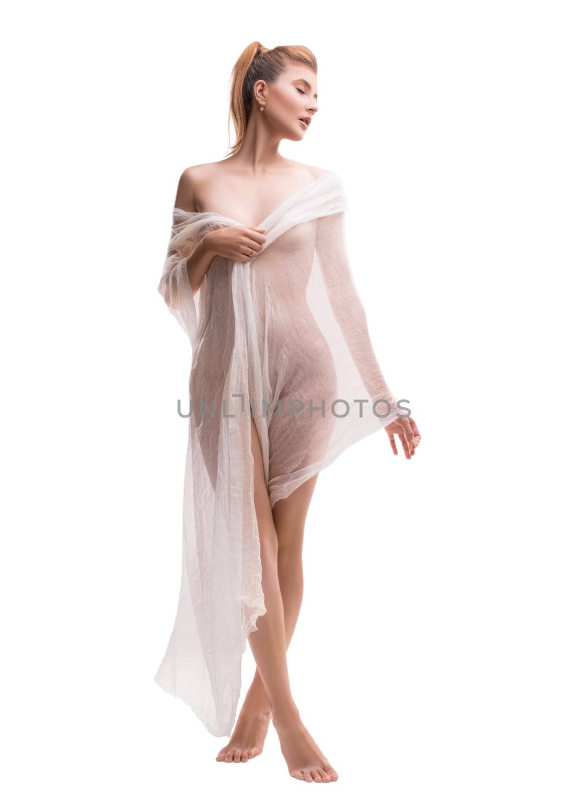 Seductive curvy female covering body with transparent cloth standing on tiptoes in studio isolated