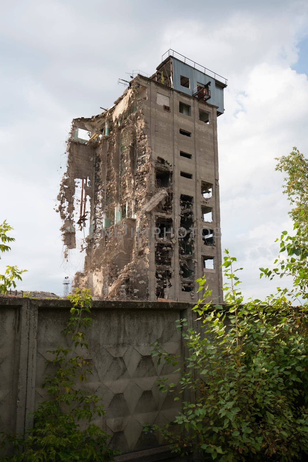Exterior of damaged abandoned building with crumbling cement walls located against gray sky