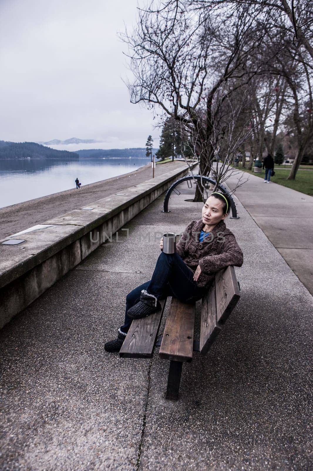 Woman sits on bench in a park in Coeur d'Alene, Idaho.