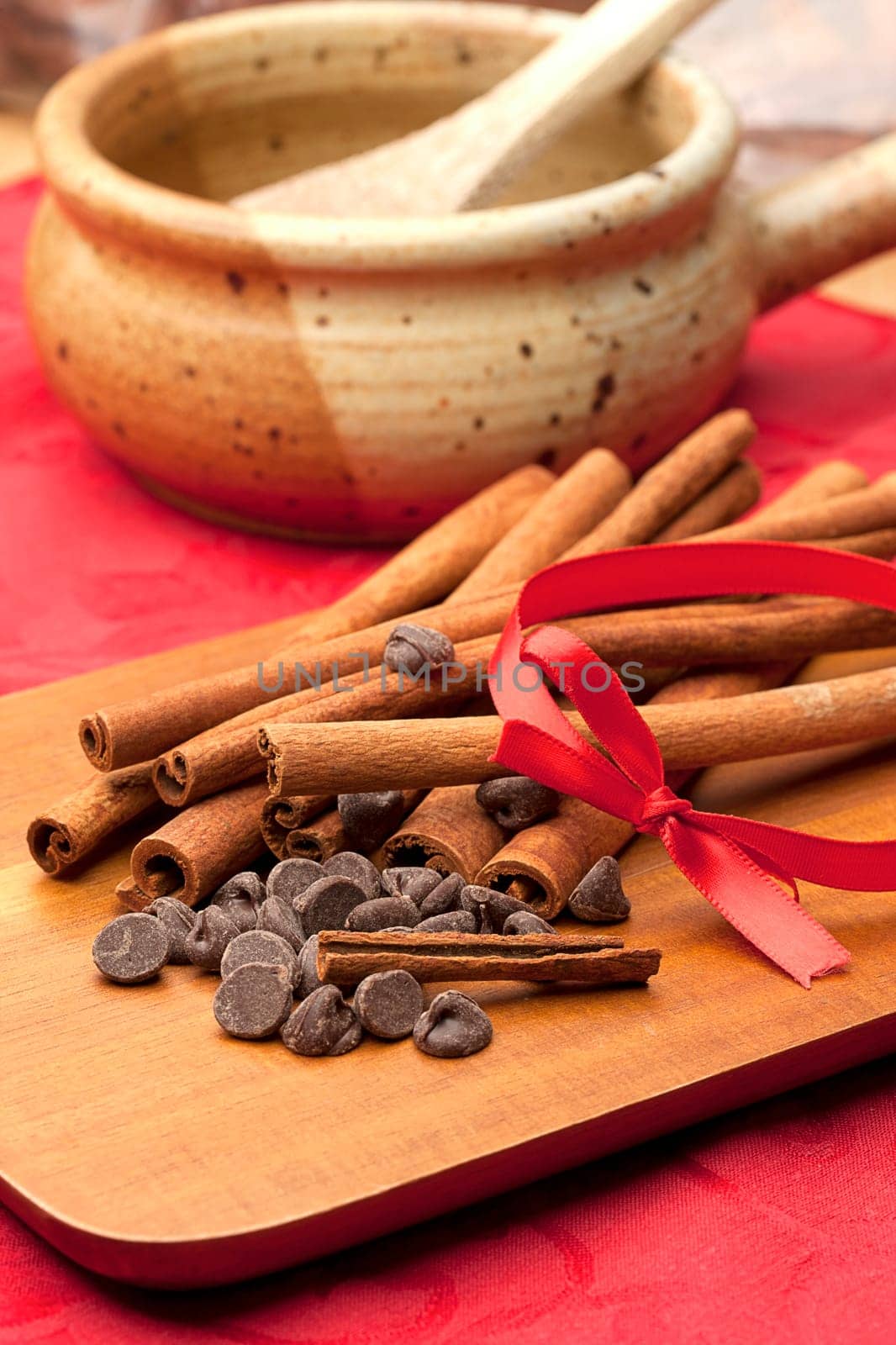 Chocolate chips and a pile of cinnamon stick together on a cutting board.