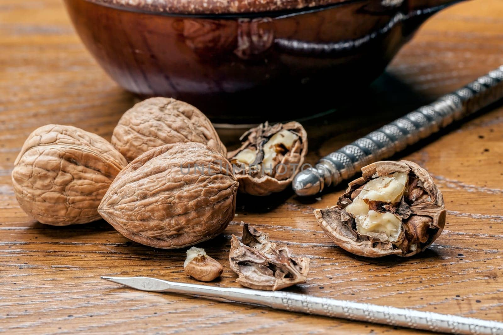 Unshelled and shelled walnuts on the table with a pick and nutcracker.