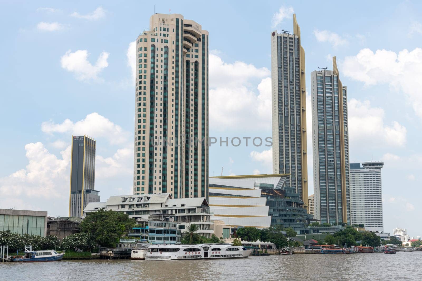 A breathtaking modern skyline displaying impressive tall buildings situated along a serene river beneath a bright sky