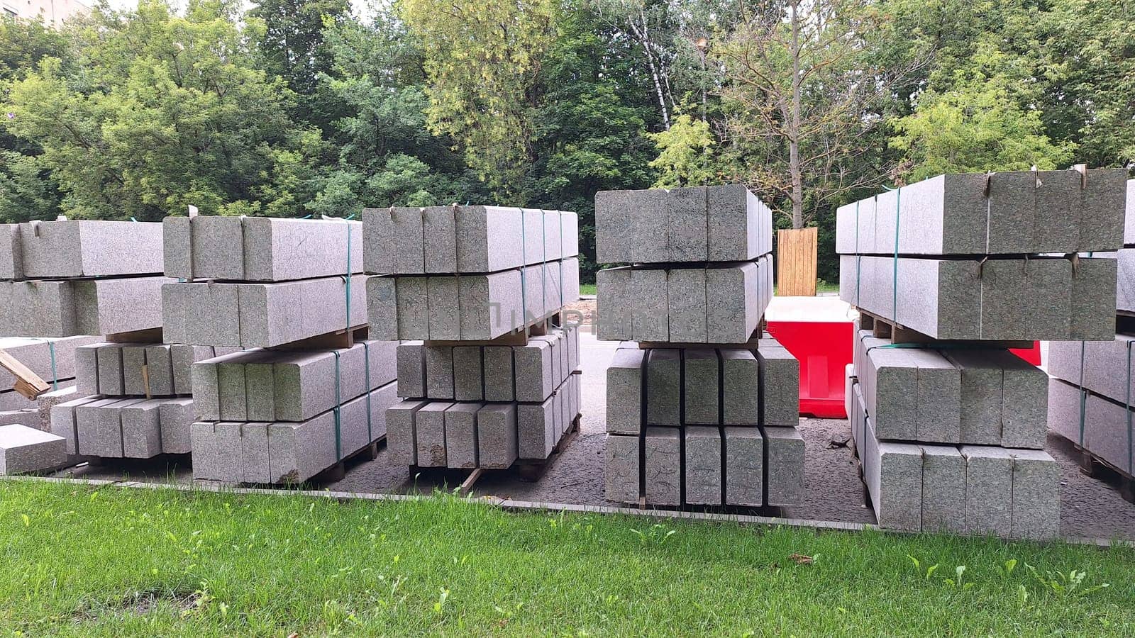Stacks of construction concrete blocks on grass with forest background.
