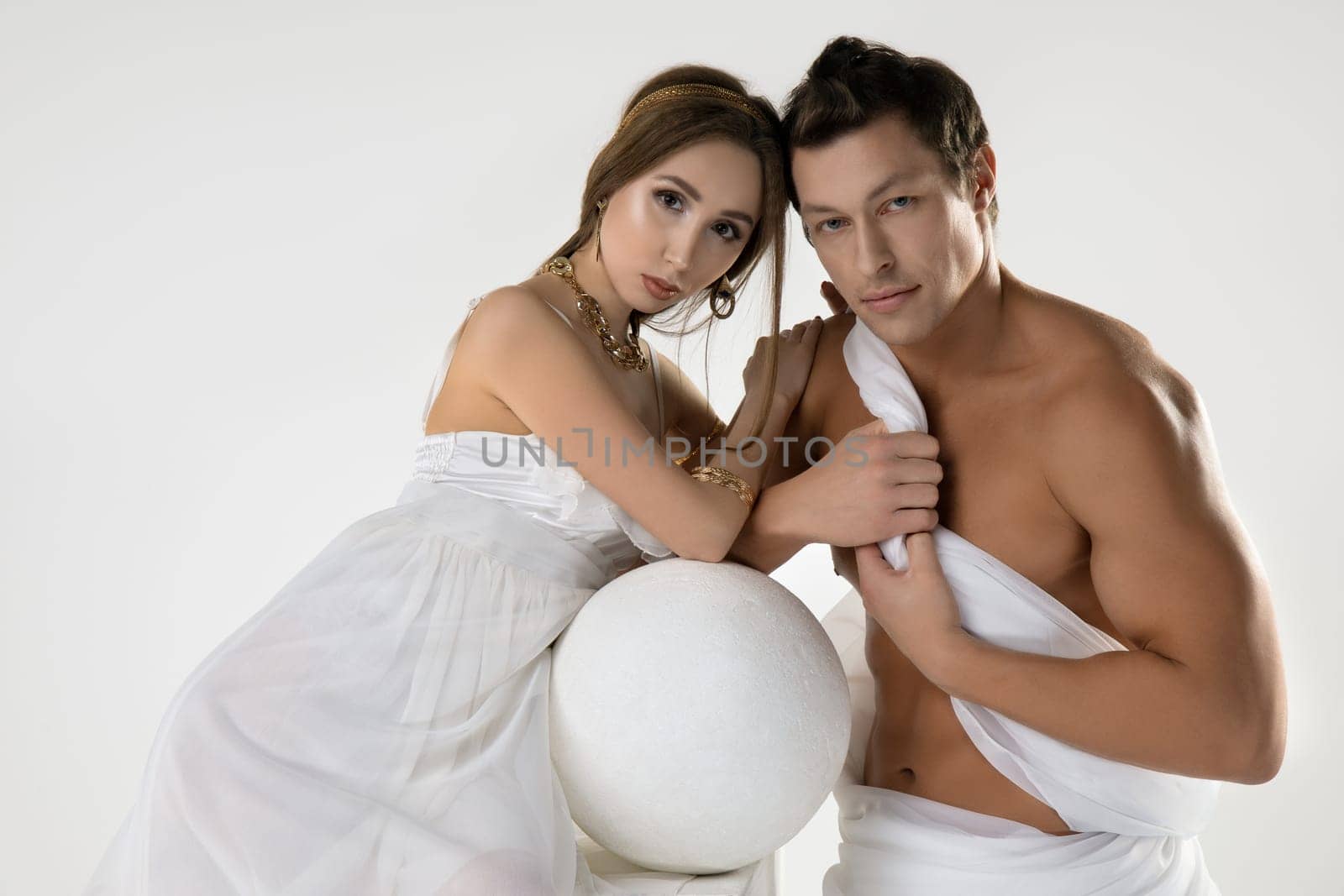 Portrait of young romantic couple in love dressed in white clothes in antique style embracing and looking at camera