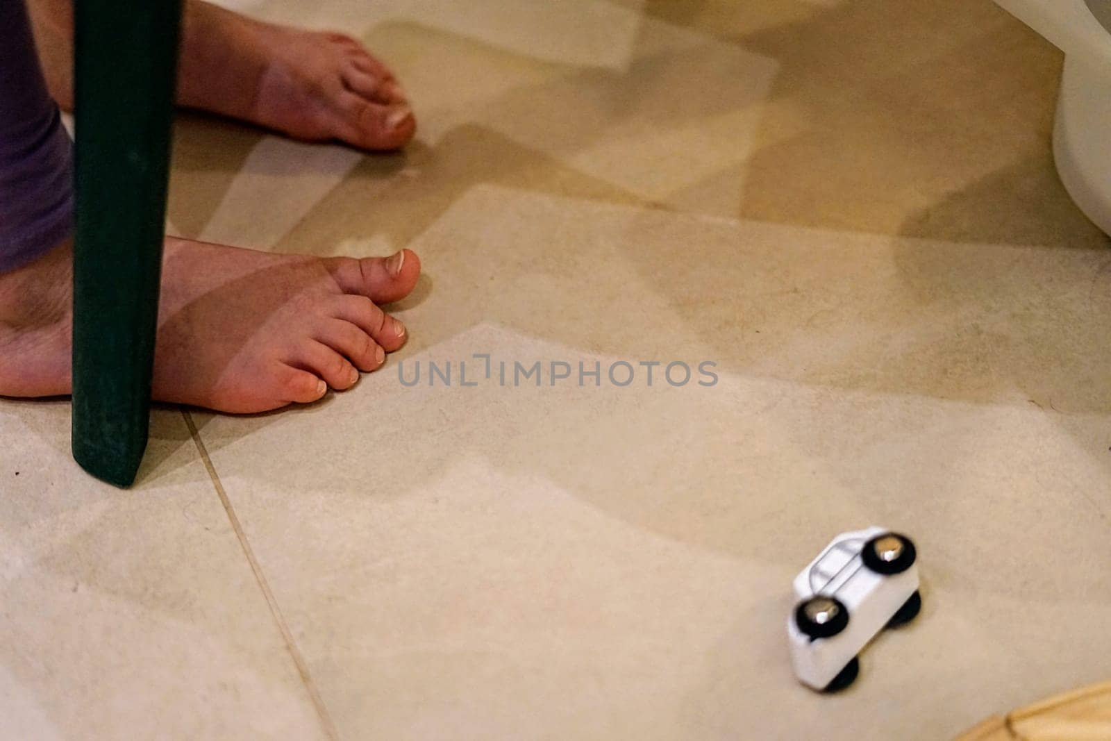 kids child bare foot on tile floor toys mess car clean home play game stay walk cold warm skin closeup healthy body small toes . High quality photo