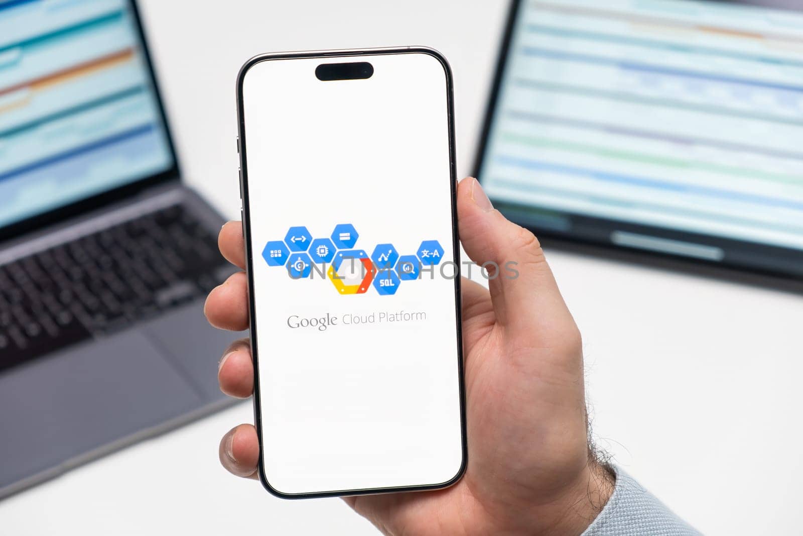 PRAGUE, CZECHIA - JULY, 2024: Google Cloud Platform logo on the screen of smartphone in mans hand and laptop on the background