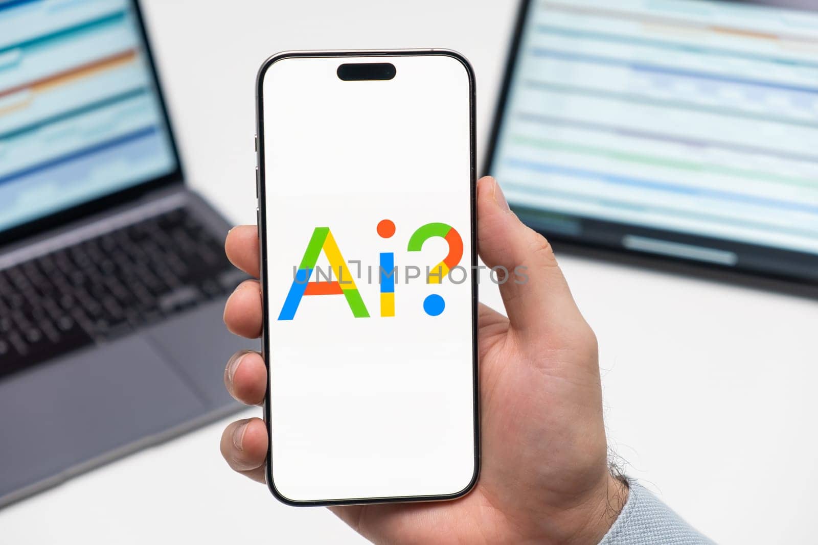 PRAGUE, CZECHIA - JULY, 2024: Google AI logo on the screen of smartphone in mans hand and laptop on the background