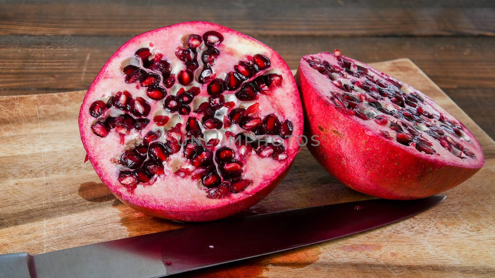 Fresh cut pomegranate halves on wooden cutboard