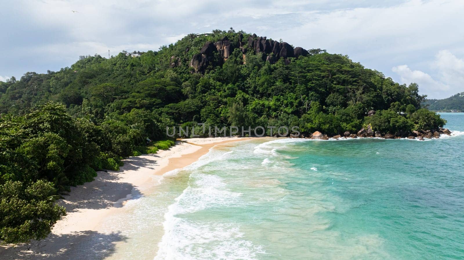 A tropical beach paradise with golden sands, crystal-clear waters, and lush green foliage. Seychelles, Mahe. Anse Louis beach.