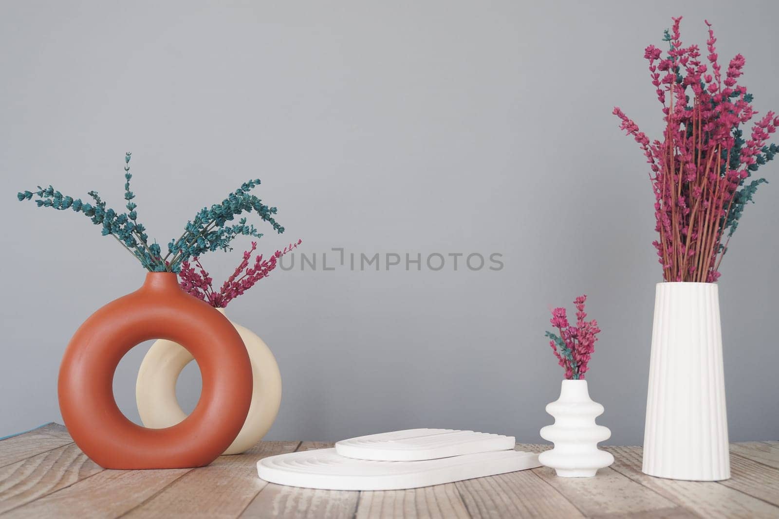 Decorative vases with dried flowers arranged on a wooden surface.