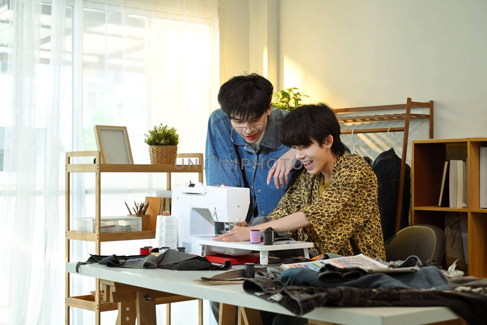Happy designers working on a new clothing project in a bright fashion studio.