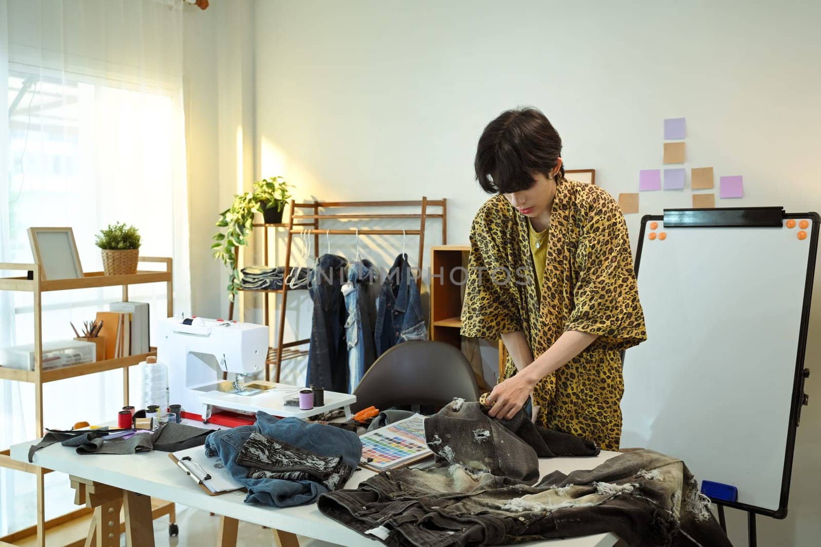 Young designer creating custom fashion pieces in a stylish workspace.