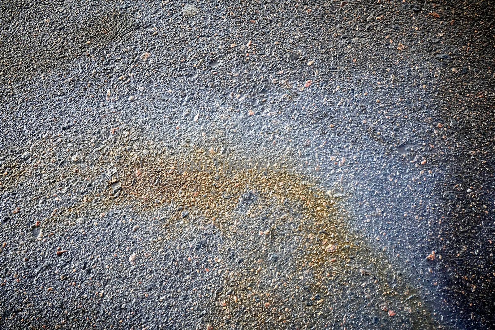 Perspective of bright petrol stains, displaying a textured ground with a range of colors on the street