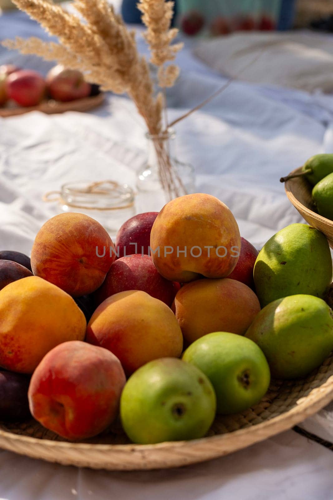 A bowl of fruit on a table. There are large ripe peaches, red and yellow, on the plate. There are also green apples.