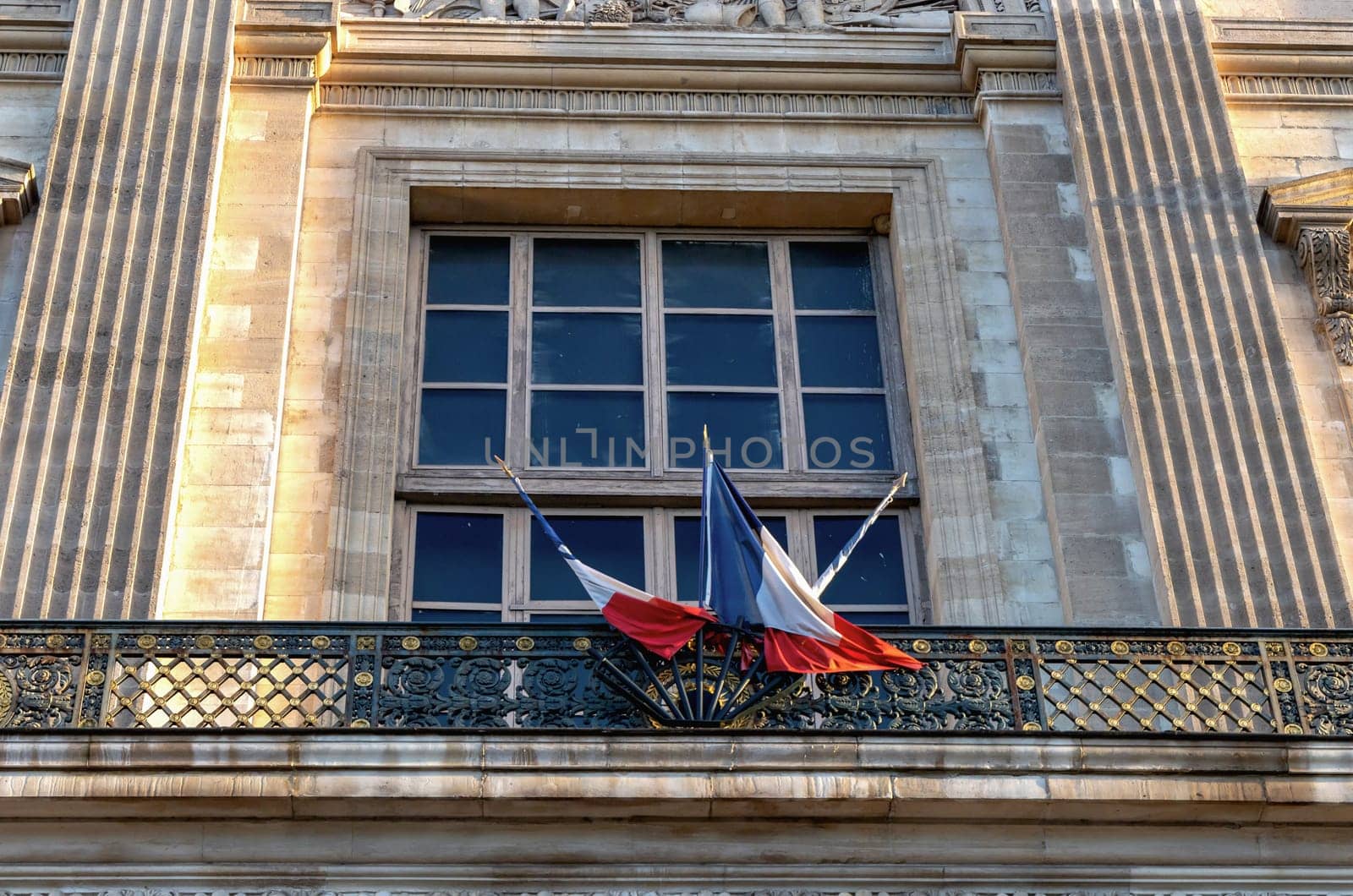 Facade of a building with a large window and French flags. Paris, France