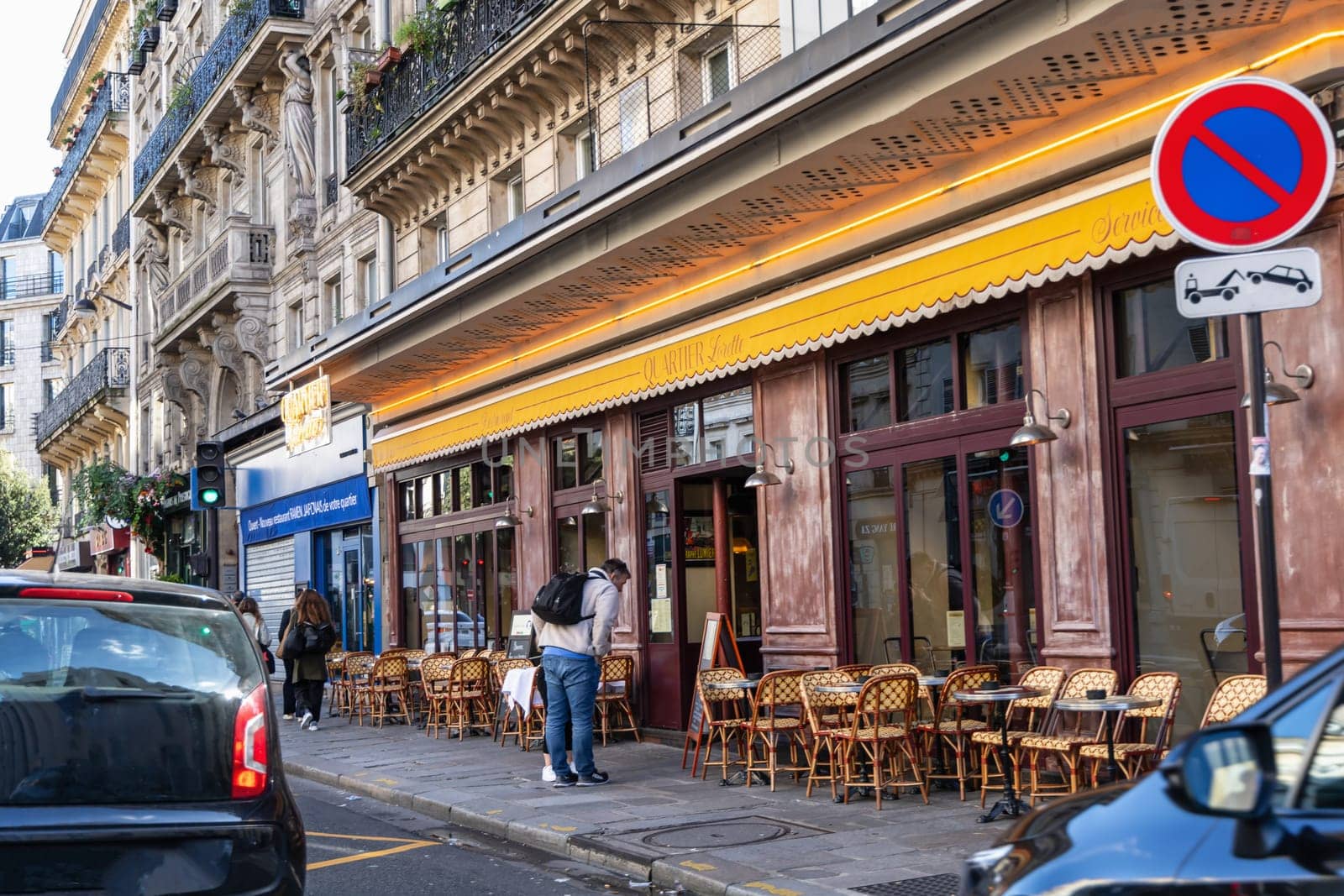 Paris with beautiful buildings, cars and people passing by on the street. Paris, France - February 10, 2025