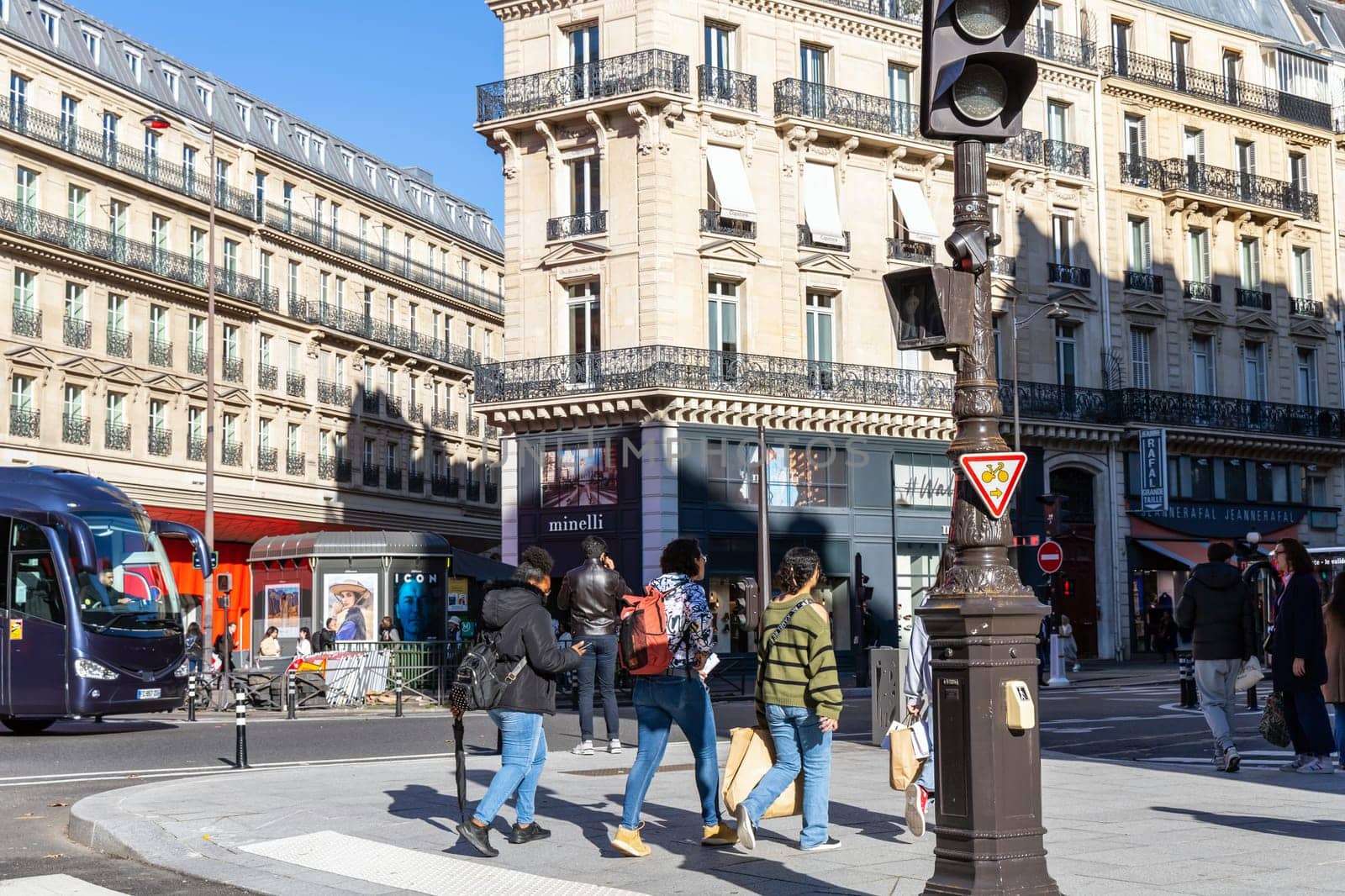 Paris with beautiful buildings, cars and people passing by on the street. Paris, France - February 10, 2025