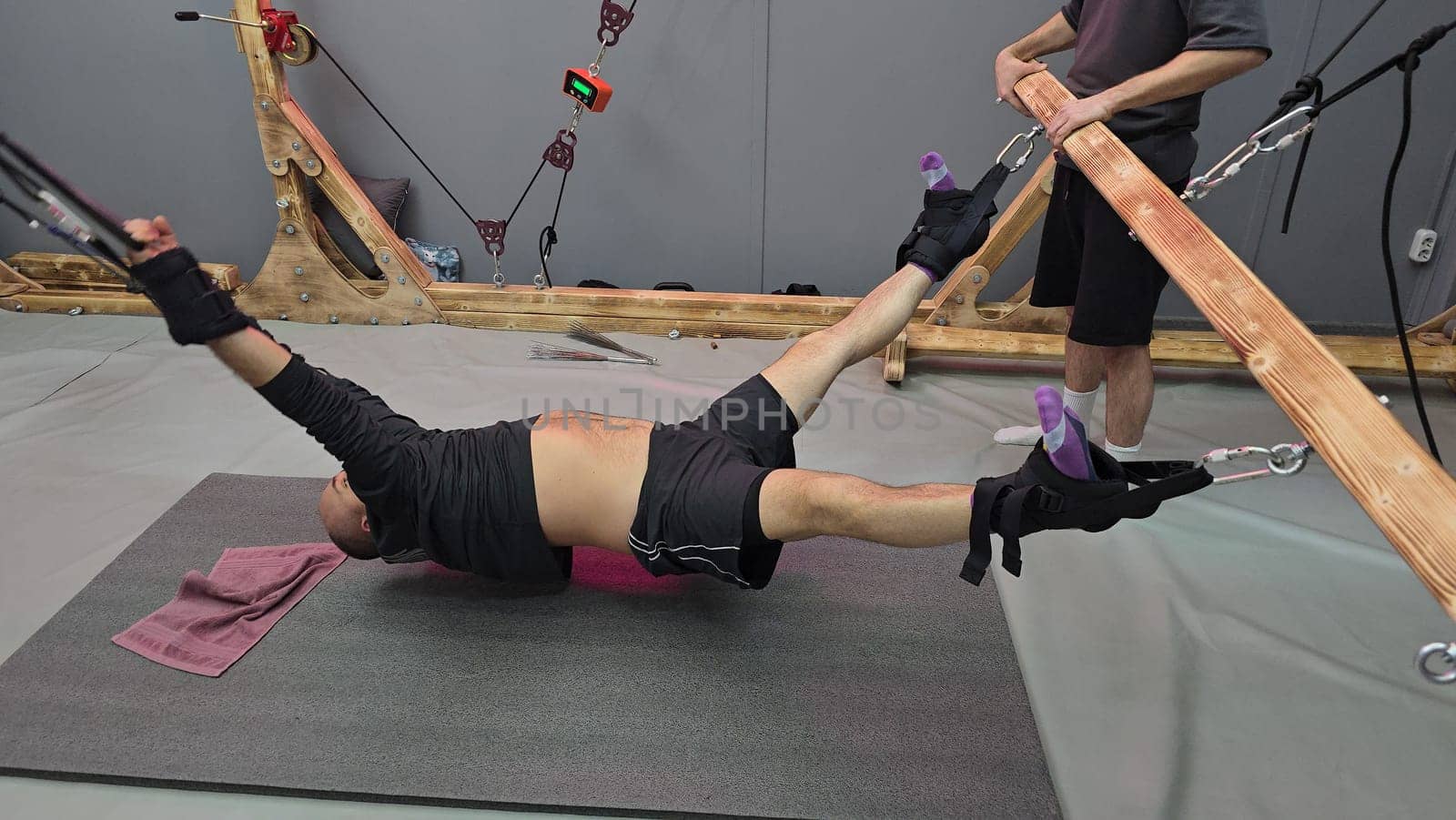 Chiropractor assisting patient undergoing spinal decompression therapy using a wooden traction table