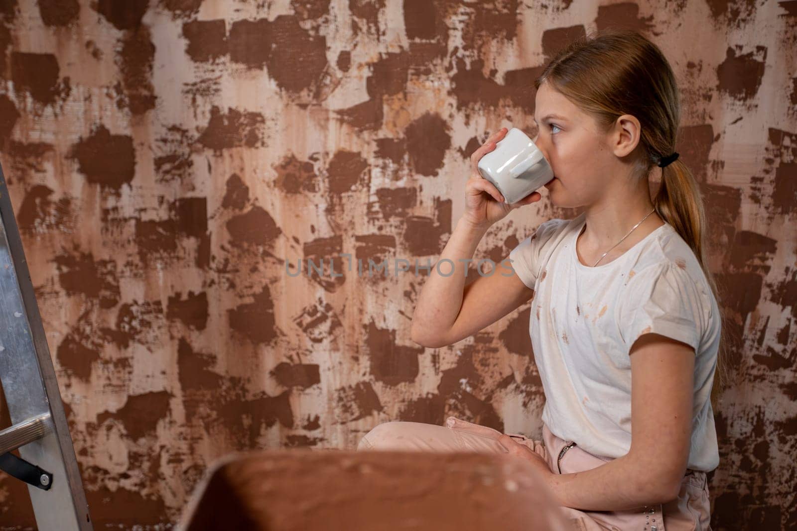 A girl enjoys a refreshing drink during home renovation, highlighting her creativity and leisure activities