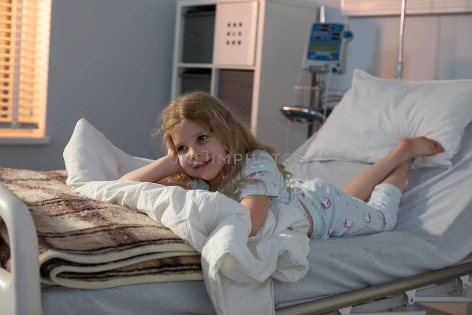 A young girl is relaxing in her hospital bed, displaying remarkable resilience and heartfelt optimism during her stay