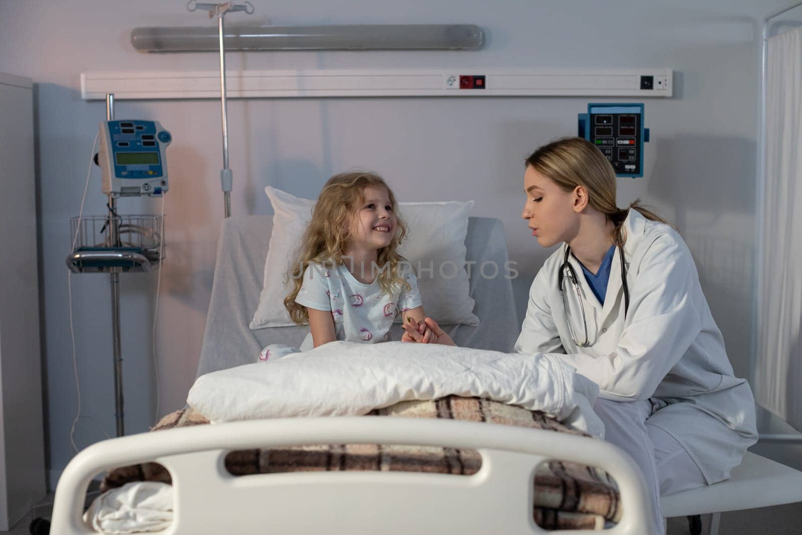 A compassionate doctor is providing comfort to a young girl in a hospital room, showcasing care and emotional support