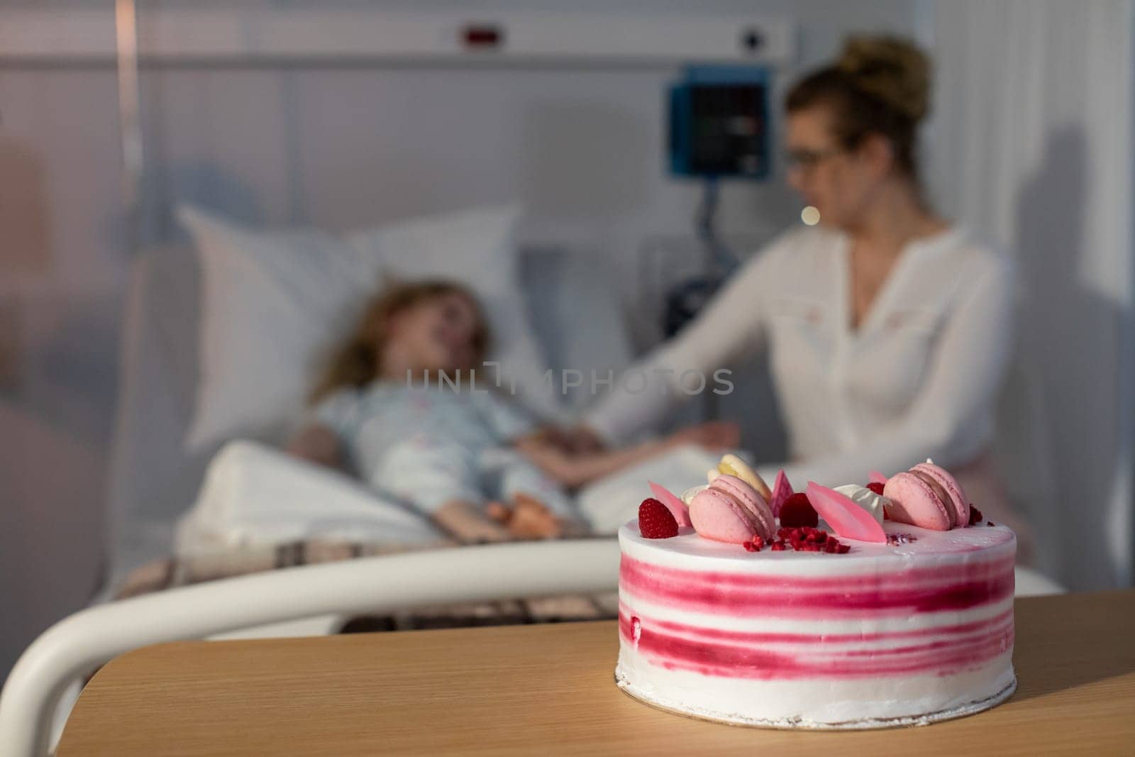 A tender moment shared between a loving mother and her child in a hospital room with a delightful cake