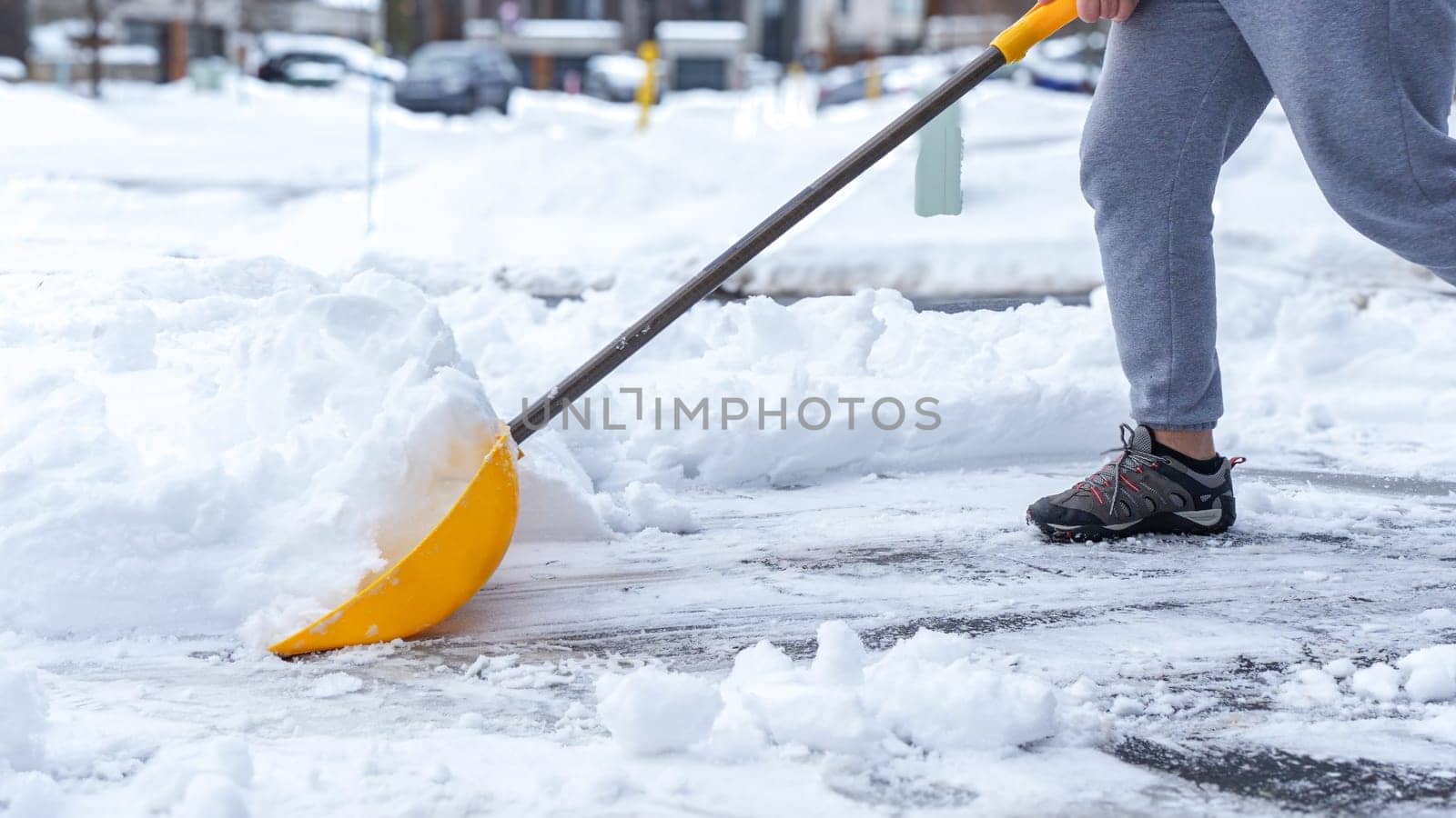 Man shoveling snow off of his driveway after a winter storm in Canada. Man with snow shovel cleans sidewalks in winter. Winter time