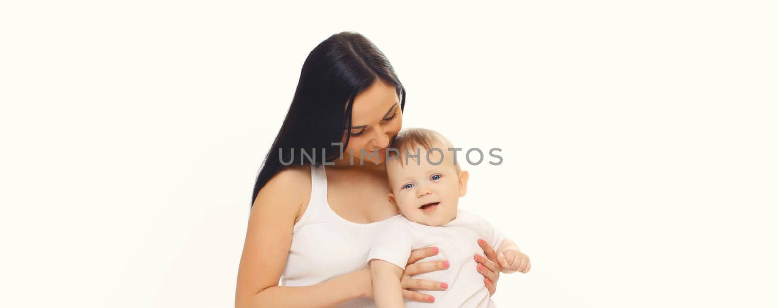 Happy smiling young mother playing with cute baby sitting together on the floor on white studio background