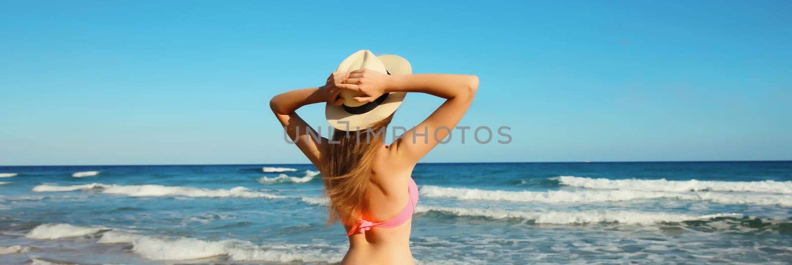 Summer vacation, relaxed beautiful young woman enjoying in bikini swimsuit, tourist straw hat on the beach on sea coast with waves