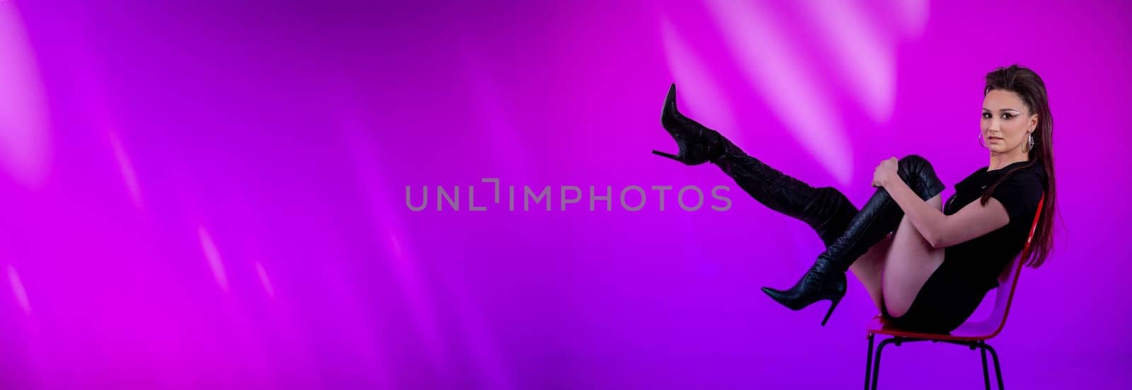The chic model confidently showcases bold and vibrant fashion against a striking purple ambiance that captivates