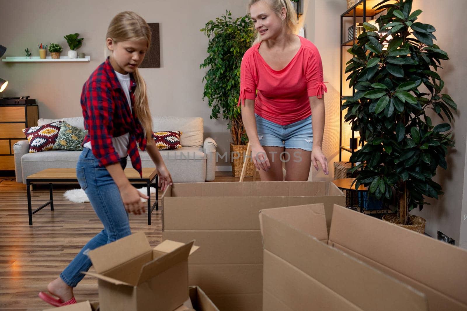 A loving mother and her daughter joyfully unpack boxes together, crafting a warm and inviting new home space