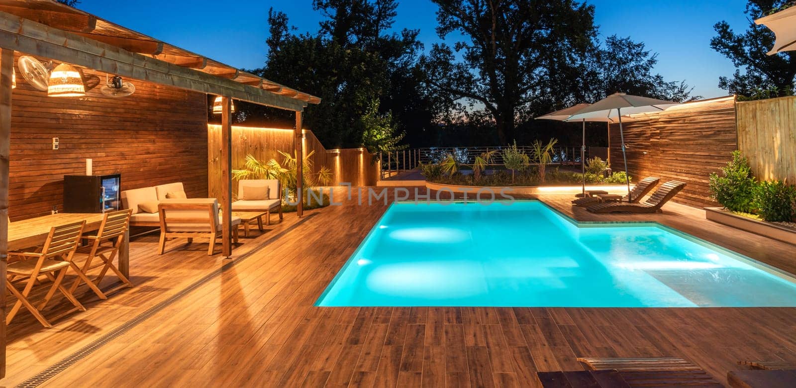 Luxurious outdoor pool area with cozy wooden deck and ambient lighting