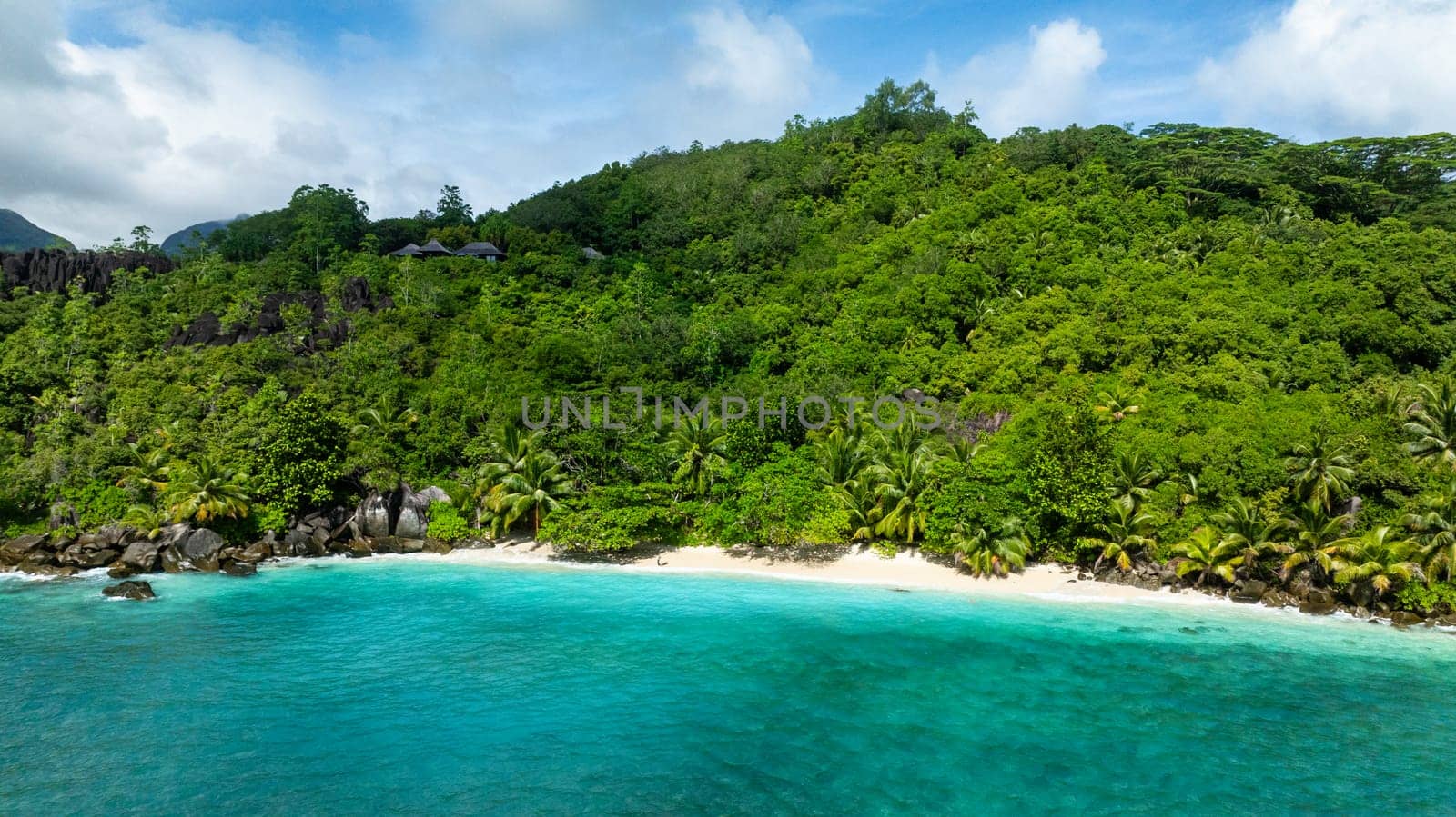 Coastline surrounded by lush vegetation and white sandy beach. Seychelles, Mahe. Butzel Beach.