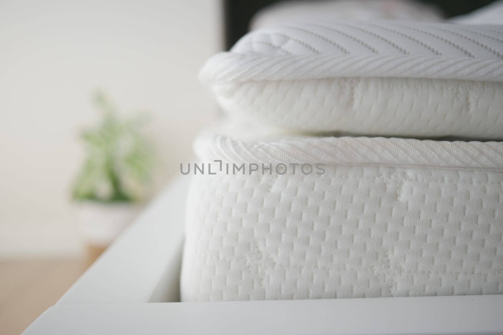 Soft white mattresses are neatly arranged on a contemporary bed frame.
