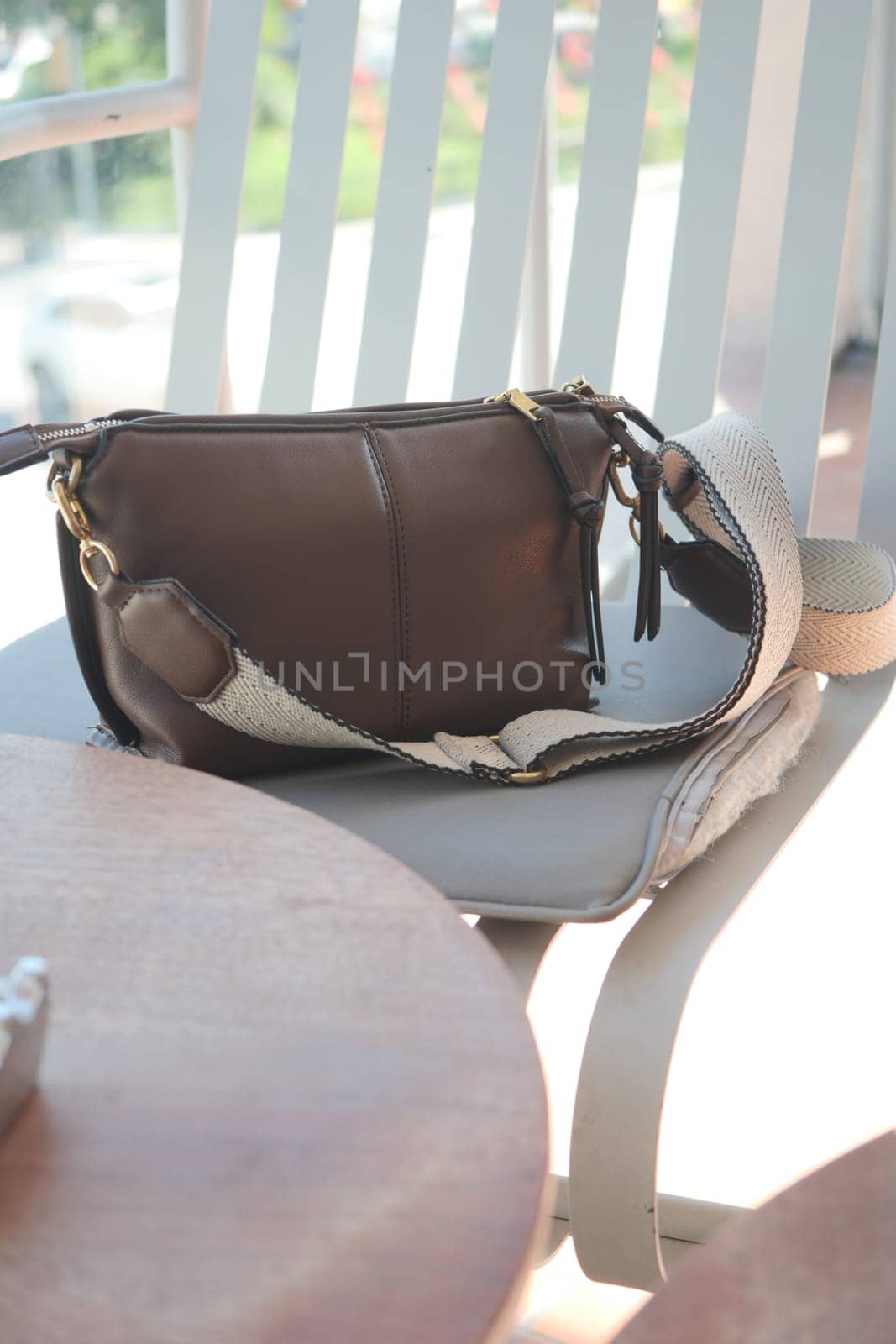 A brown handbag rests on a chair at an outdoor cafe, inviting calm.