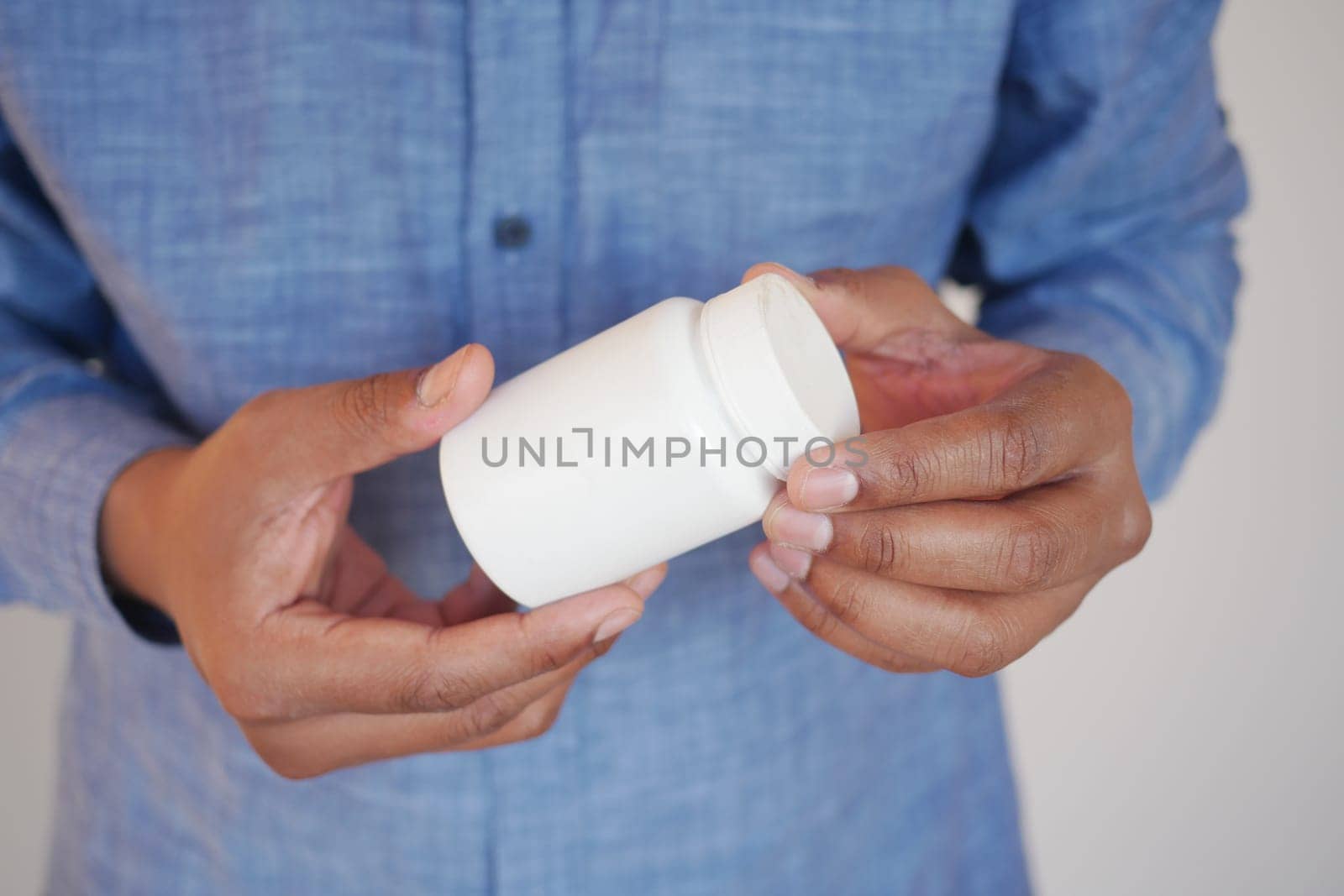 Individual examines a small white bottle with interest indoors.