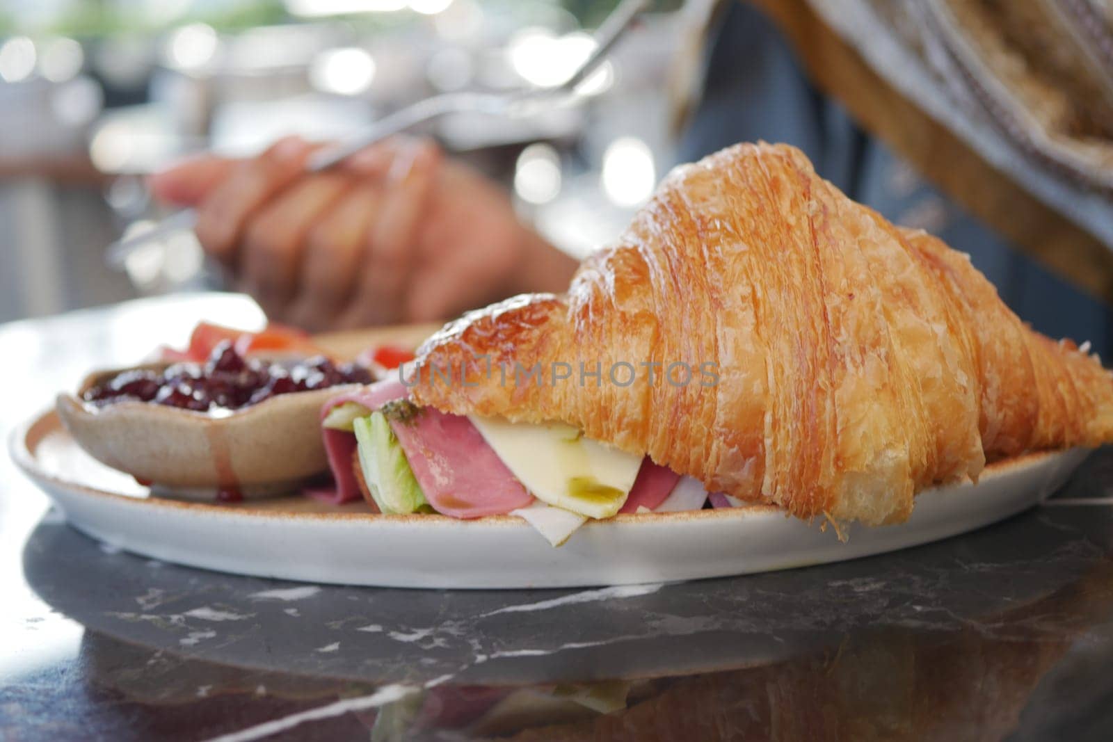 Enjoying a tasty croissant filled with ham and cheese at breakfast.